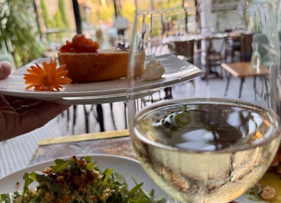 Delicious dessert, fresh salad, and glass of white wine in a charming garden setting.